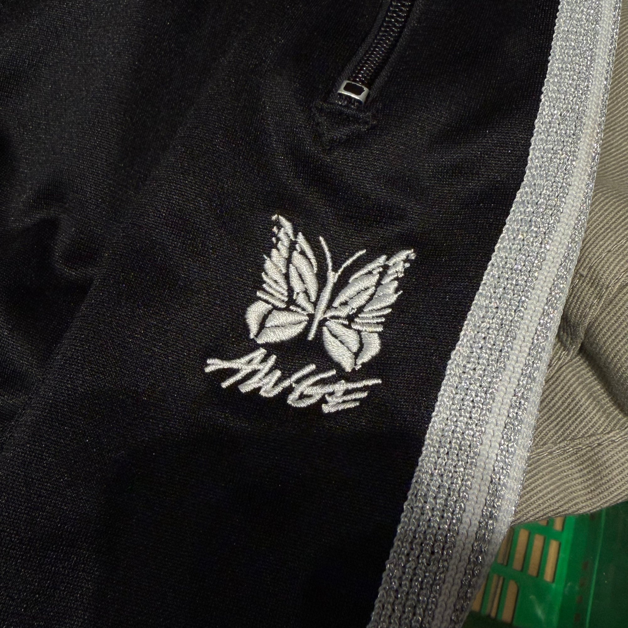 NEEDLES X AWGE TRACK PANTS ‘BLACK/SILVER’
